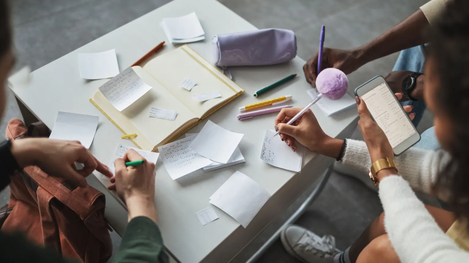 Pessoas adultas organizam anotações e materiais em uma mesa